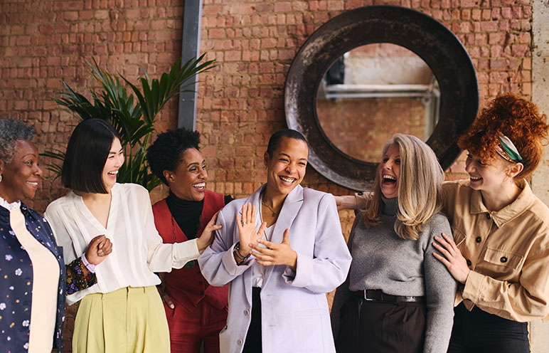 A group of six women laughing and smiling all together