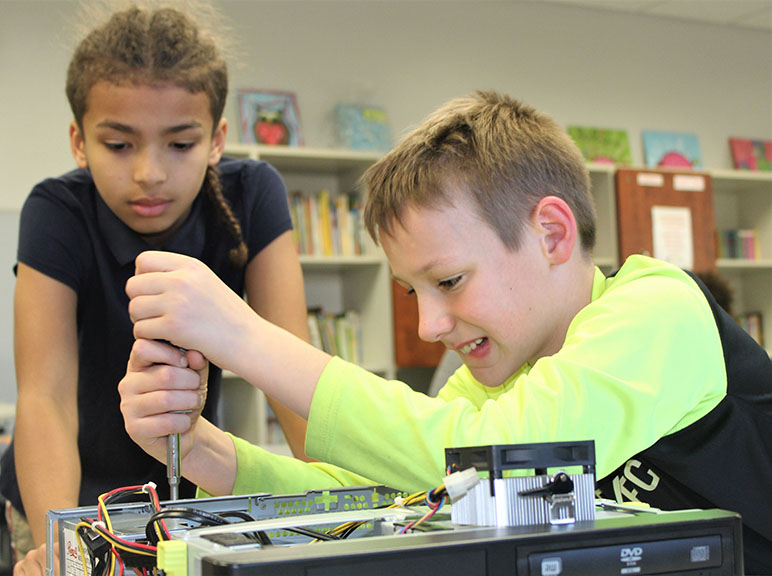 A young boy and girl playing with a computer monitor