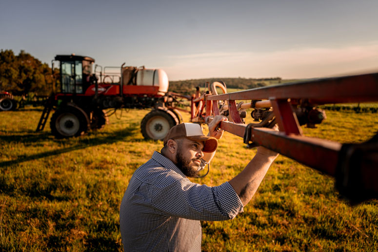 A farmer examines a piece of farm machinery