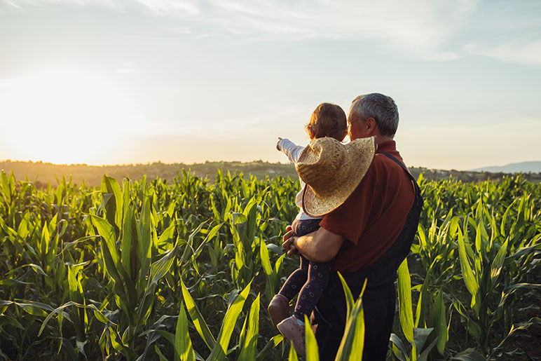 Farmer with his grandchild looking at a farm for farm insurance costs