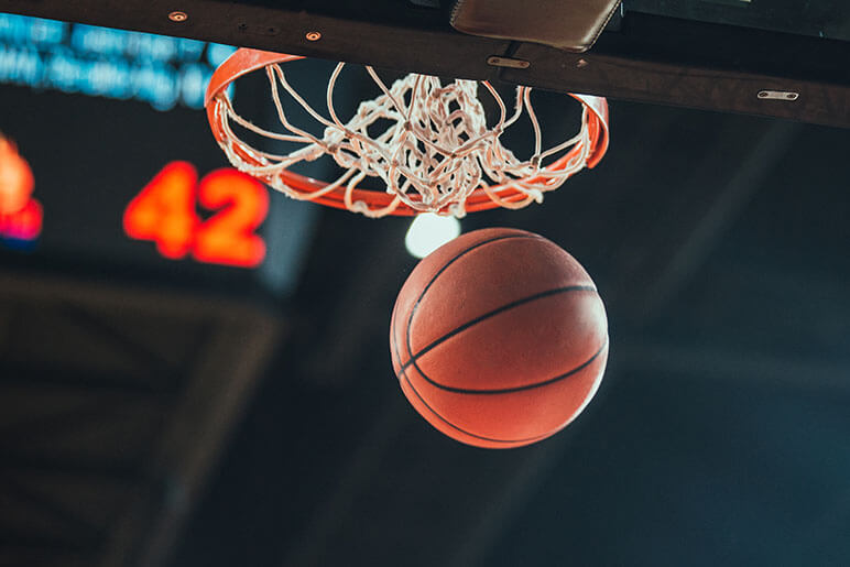 Basketball swishing through the basketball hoop with the scoreboard showing 42 points in the background