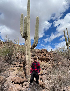 James standing by a cactus on a mountain side