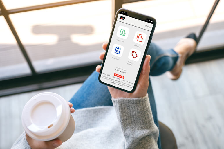 Woman holding a cup of coffee and her mobile phone with the Indiana Farm Bureau Insurance app open on the phone