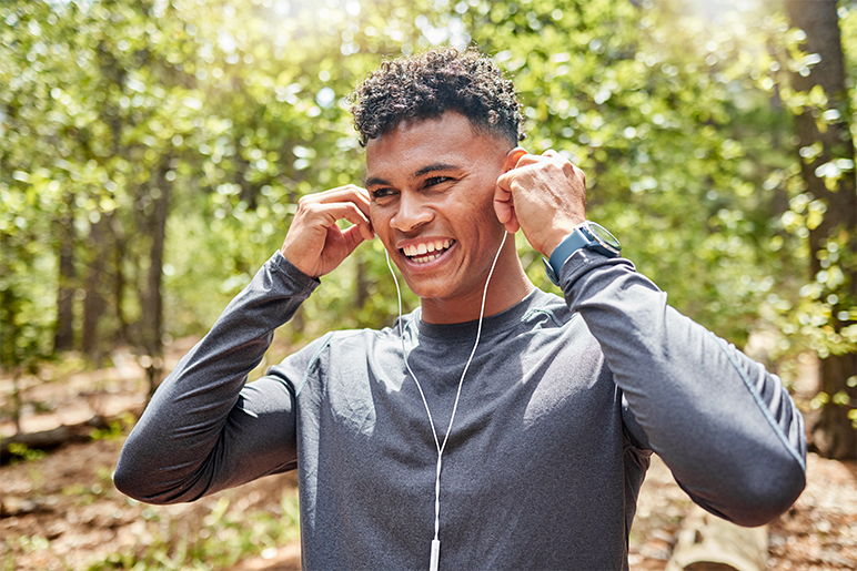 Photo of young adult in the sunny woods working out with headphones on
