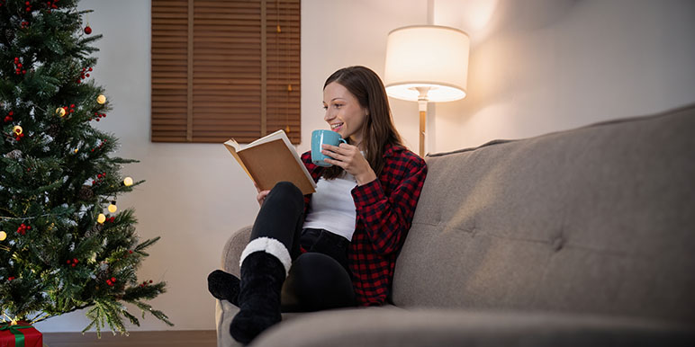 Tips to stay positive during the holiday season woman sitting on the couch reading