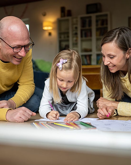 Mom and dad on the ground drawing with their daughter